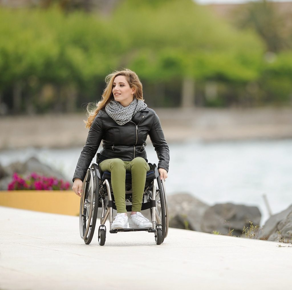 young woman in a wheelchair on a path next to water