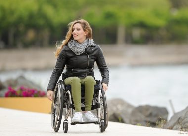 young woman in a wheelchair on a path next to water