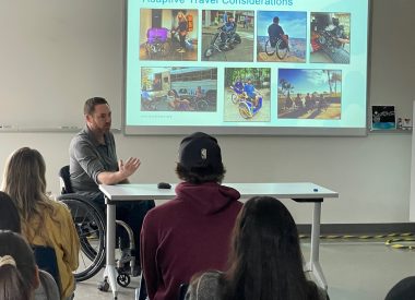 classroom session with teacher in wheelchair at front of class with presentation